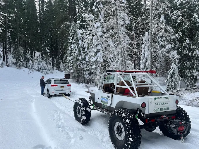 Ridgeline Towing rock crawler winching an SUV out of deep snow on a Sierra Nevada forest road