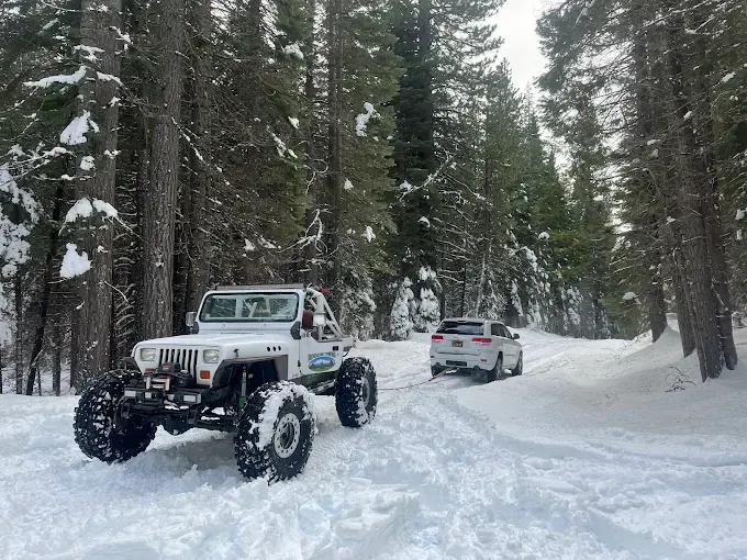 Ridgeline Towing recovery rig pulling a stuck vehicle through snow-covered pines