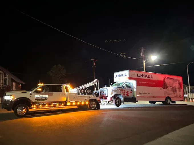 Ridgeline Towing wrecker towing a U-Haul box truck at night in Gold Run, California