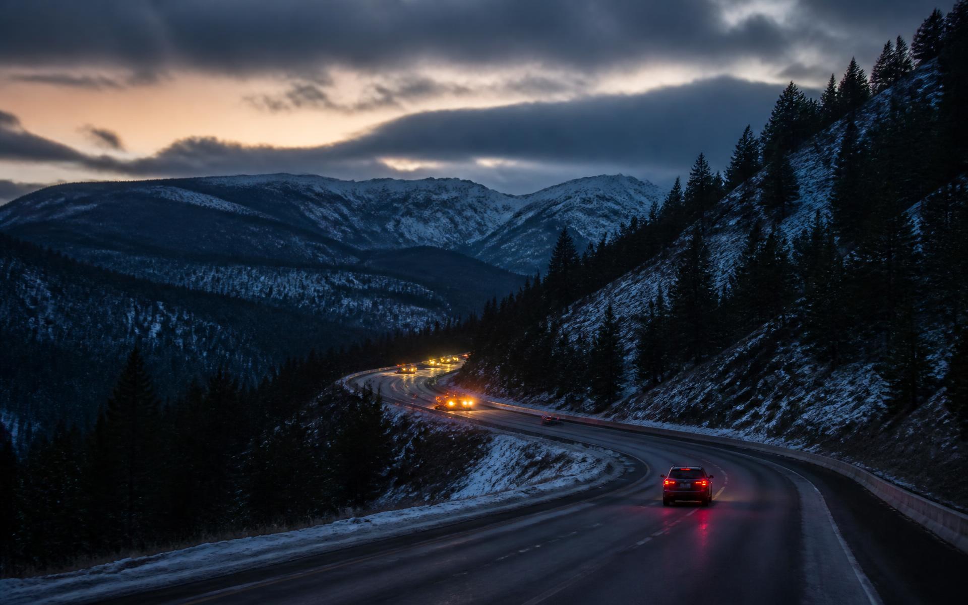 Winding I-80 mountain highway at dusk through the snow-dusted Sierra Nevada near Gold Run, California